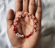 a hand holding a beaded bracelet with the word love spelled in beads on it