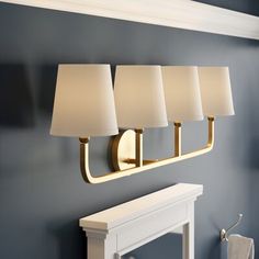 three lamps mounted on the wall next to a white fire place and fireplace mantel