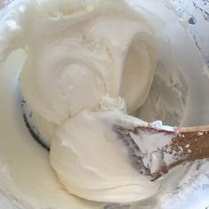 a wooden spoon mixing white cream in a bowl