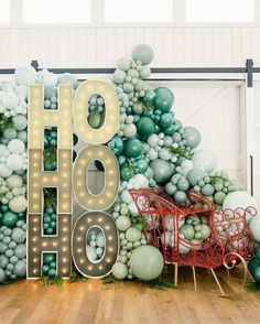 a large sign that says ho hoo with balloons around it and a sleigh on the floor