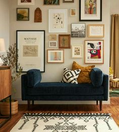 a blue couch sitting in front of a wall filled with pictures and framed art on it