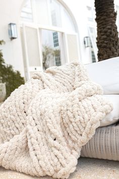 a pile of blankets sitting on top of a bed next to a palm tree in front of a house