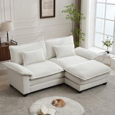 a white sectional sofa with pillows and a book on the floor in front of it