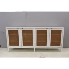 a white cabinet with wicker doors on the front and bottom, against a gray wall