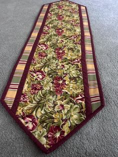 a neck tie laying on the floor in front of a carpeted area with flowers