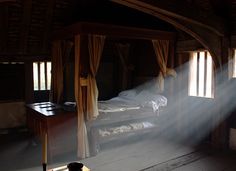 the sun shines through the curtains in an old fashioned bedroom with two beds and a desk