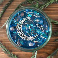 a glass jar filled with lots of blue and green things on top of a wooden table