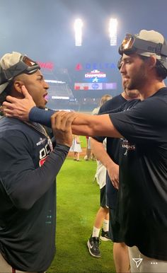 two men standing next to each other on top of a field at a baseball game