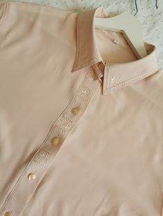 Vintage embroidered polyester top from the 1990's. Women's button up blouse in pastel pink with embroidered collar. Has an oversized boxy shape and short sleeves. The top is made of silky polyester fabric, which feels very nice to the skin. Material: 100% Polyester Size: Marked 48 DE, which is 2XL, but fits more like XL. To be sure this item would fit you, please look at the measurements below. Approximate measurements (taken when shirt is lying flat, double armpit to armpit and waist): Shoulder Pink Embroidered Button-up Blouse, Vintage Pink Blouse With Button Closure, Pink Embroidered Collared Top, Vintage Pink Buttoned Shirt, Vintage Pink Shirt With Buttons, Vintage Pink Shirt With Button Closure, Pink Button-up Tops With Floral Embroidery, Pastel Color Shirts, Hipster Tops