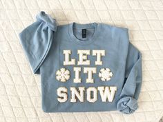 "Custom made Christmas chenille letter crewneck sweatshirt. Features \"Let it snow\" in beautiful chenille letters and chenille snowflake patches. Makes an adorable Christmas shirt that will be sure to bring Christmas cheer to everyone all winter! Need this ASAP? see bottom of listing for rush order link ⭐️ Crewneck sweatshirt is a unisex Gildan size small-3XL. See size chart in listing pictures. 50% cotton, 50% polyester.  ⭐️ Youth sizes also available. All youth shirts will be made with the smaller 2.1\" Letters! ⭐️ Made with a \"Carolina blue\" Gildan crewneck sweatshirt and white chenille patches. Want to customize colors? no problem! Please specify color requests when ordering  ⭐️ wash on delicate with cold water. Hang dry is recommended  ⭐️ Check out my shop for other Christmas desig Cheap Letter Print Sweatshirt For Gifts, Puff Paint Christmas Sweatshirt Diy, Iron On Letter Sweatshirt Ideas, Iron On Patches Sweatshirt Ideas, Christmas Sweatshirts Vinyl, Patch Ideas, Beaded Projects, Chenille Patches, Thanksgiving Craft