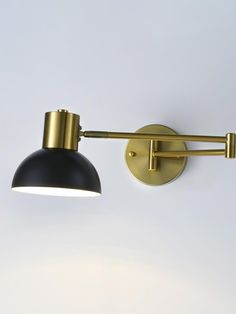 a black and gold wall light on a white wall next to a gray lamp shade