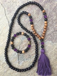 108 bead mala & bracelet 108 bead mala with 100% Egyptian cotton, handmade tassel. Made with: Matte black wooden beads (8mm), brown robles wood beads (8mm), Lava rock (8mm), matte purple glass beads (8mm) These 108 beaded necklace measures 29 inches in lengthThe total hanging length is 18 inches. Tassel is 2.5 inches The symbol of the Buddha, with his compassionate smile, reminds us to strive to develop kindness, peace & love so that we can be a true friend to all beings. Lava stone is o Holistic Round Beads Jewelry For Yoga, Spiritual 108 Beaded Jewelry For Yoga, Purple Bohemian Beaded Bracelets For Meditation, Spiritual Jewelry With 108 Beads For Yoga, Holistic Jewelry With 8mm Beads For Yoga, Holistic Yoga Jewelry With 108 Beads, Adjustable Spiritual Mala For Yoga, Bohemian Brown Mala With Natural Stones, Black Bohemian Mala With Round Beads