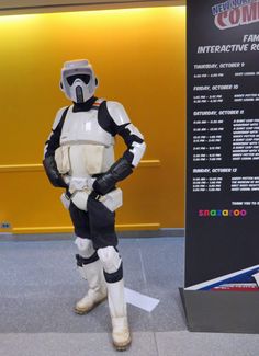 a man dressed as storm trooper standing next to a sign