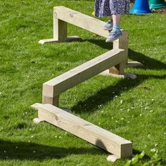 a person standing on top of a wooden bench in the middle of some green grass