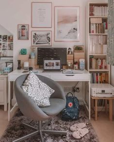 a desk with a chair, laptop and bookshelf