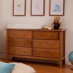 a baby's room with a dresser, crib and pictures on the wall