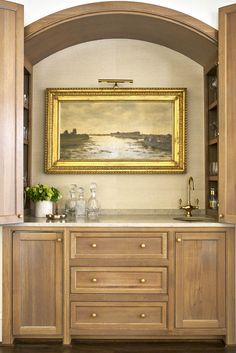 a painting hanging on the wall above a kitchen counter with drawers and cabinets below it