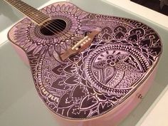 a pink and black guitar with intricate designs on it's body, in a case