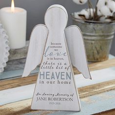 a wooden angel with the words heaven is in heaven on it's side and a candle next to it