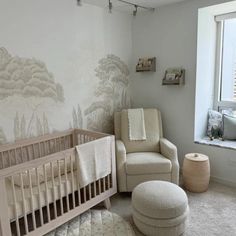 a baby's room with a crib, chair and ottoman in the corner