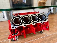 a red engine block sitting on top of a wooden floor next to a glass table