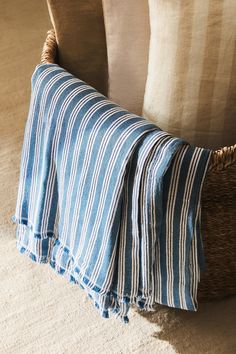 a blue and white striped blanket sitting on top of a chair next to a pillow