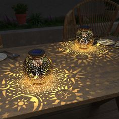 two vases sitting on top of a wooden table covered in sun and moon designs