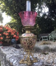 a pink glass vase sitting on top of a stone wall