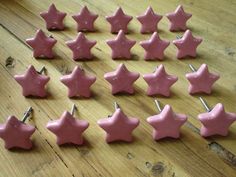 there are many pink stars on the wooden table and one is missing it's ear pins