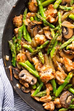 chicken and asparagus stir - fry in a skillet with a blue towel