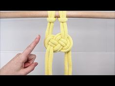 a hand is pulling a yellow rope on a wooden pole