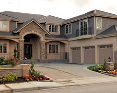 a large house with two car garages on the front and one story home in the back