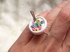 a person is holding a small ring with beads in it and two forks sticking out of it