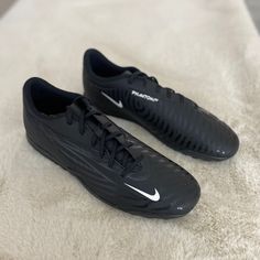 two black nike soccer shoes sitting on top of a white blanket