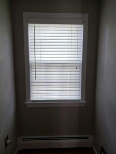 an empty room with a window and white blinds