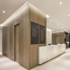 an office lobby with marble counter tops and wood paneling on the walls, along with two black framed posters