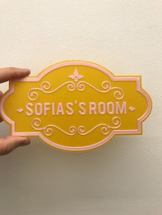 a person holding up a yellow sign that says sofias's room on it