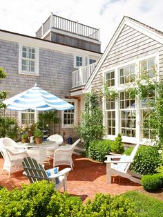 a patio with chairs and an umbrella in front of a house