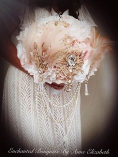 a woman in a white dress holding a pink and gold brooch with feathers on it