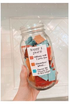 a person holding a jar filled with colorful pieces of paper and some words on it