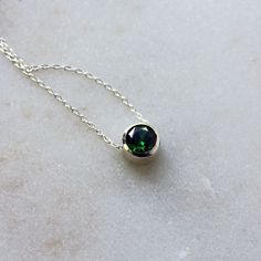 A deep green cubic zirconia, beautifully faceted for maximum sparkle, is set entirely in sterling silver in this versatile necklace, perfect for layering. A slim but sturdy sterling silver chain slides freely through the setting, and the necklace is finished with a simple spring ring clasp. The round faceted emerald CZ measures 6mm in diameter. Choose your perfect necklace (measured end-to-end including clasp) length from the drop-down menu. The last photo shows the same size gemstone and settin Minimalist Green Emerald Necklace In Sterling Silver, May Birthstone Necklace In Cubic Zirconia, Green Minimalist Cubic Zirconia Jewelry, Minimalist Green Cubic Zirconia Jewelry, Green Sterling Silver Birthstone Pendant Necklace, Green Pendant Birthstone Necklace In Sterling Silver, Green Sterling Silver Pendant Birthstone Necklace, Green Sterling Silver Birthstone Necklace Gift, Green Birthstone Necklace In Sterling Silver As Gift