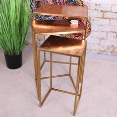 a gold metal and wood table next to a potted plant