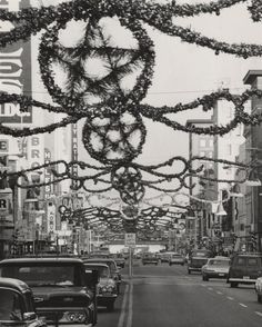 cars are driving down the street with christmas decorations hanging from it's wires above them