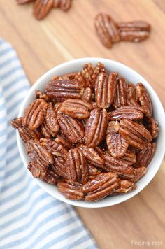 a white bowl filled with pecans on top of a wooden table