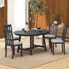 a dining table with four chairs and a potted plant in the corner next to it