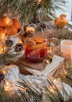 a glass jar filled with liquid sitting on top of a table next to pine branches