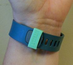 a wristband with an electronic device attached to it's side, on someone's wrist