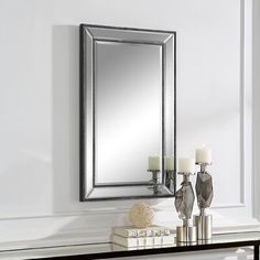 a mirror sitting on top of a table next to a vase with candles in it