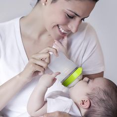 a woman is holding a baby and feeding it with a bottle