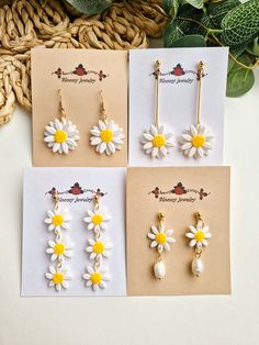 four pairs of earrings with daisies on them